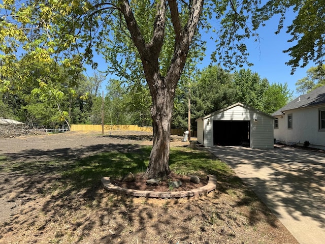 view of yard with a garage, fence, an outdoor structure, and concrete driveway