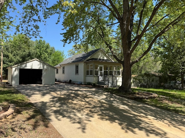view of front of property with a detached garage, an outdoor structure, concrete driveway, and covered porch