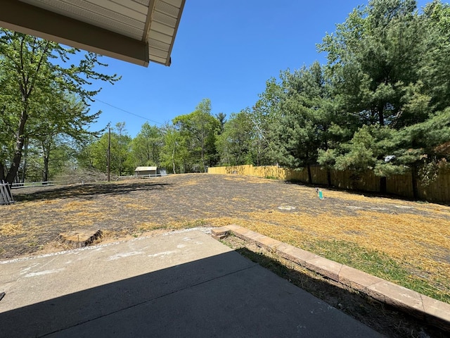 view of yard with a patio area, fence, and view of wooded area