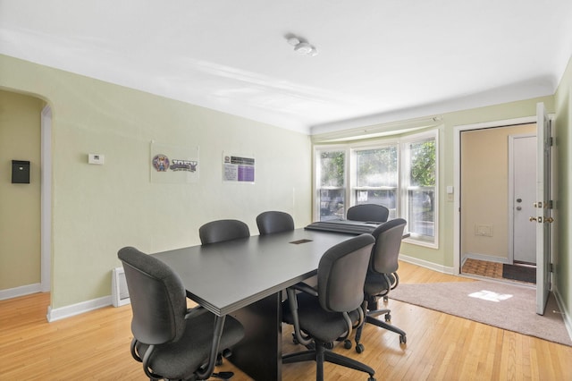 office area featuring baseboards, arched walkways, and light wood finished floors