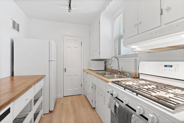kitchen with visible vents, light wood-type flooring, a sink, white cabinets, and white appliances