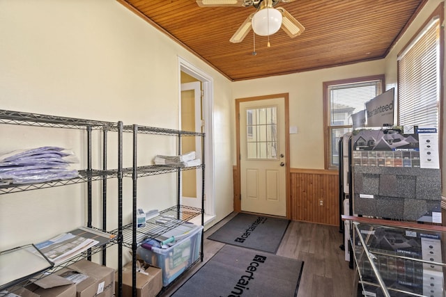 doorway with wooden walls, ceiling fan, a wainscoted wall, wooden ceiling, and wood finished floors