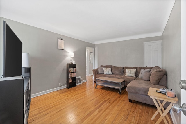 living area with baseboards, visible vents, and light wood-style flooring