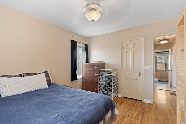bedroom with baseboards, wood finished floors, and visible vents