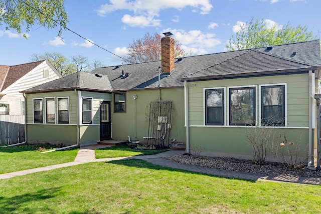rear view of property with a lawn, fence, a chimney, and roof with shingles