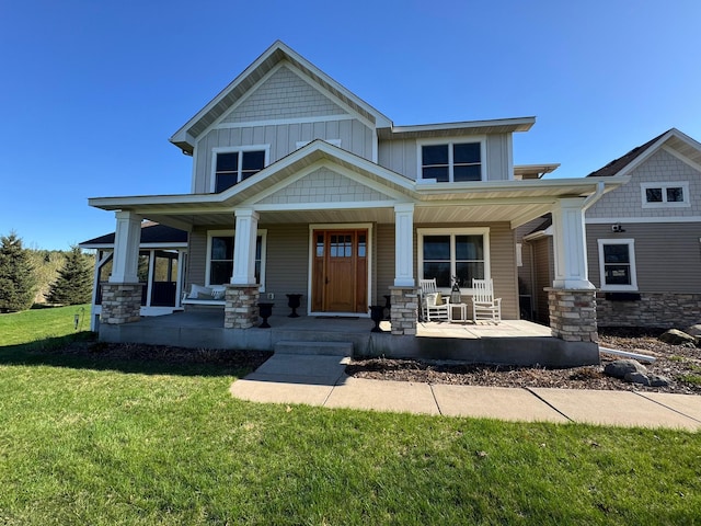 craftsman house with covered porch, stone siding, and a front yard