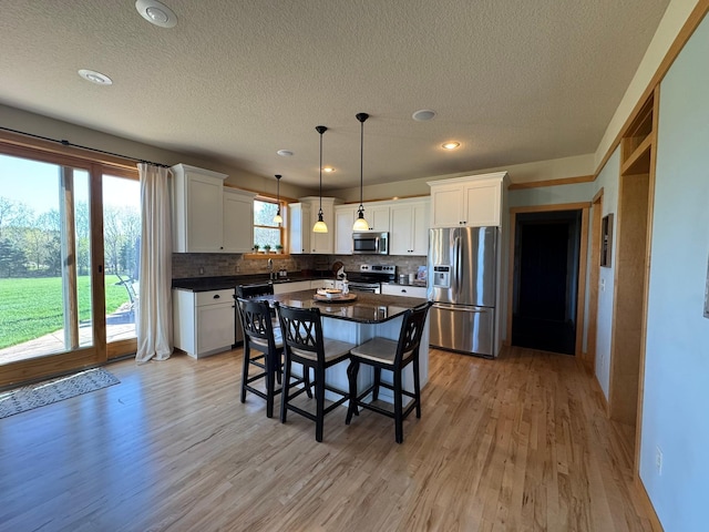 kitchen featuring dark countertops, tasteful backsplash, stainless steel appliances, and a textured ceiling
