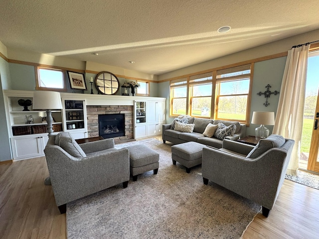 living area featuring a textured ceiling, a wealth of natural light, wood finished floors, and a fireplace