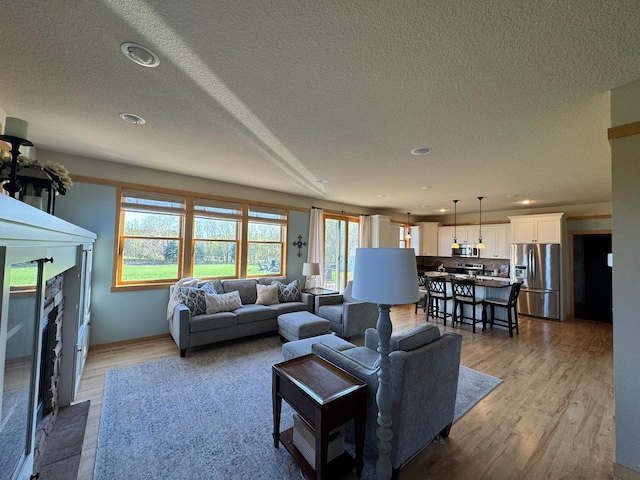living area with recessed lighting, a textured ceiling, a fireplace with flush hearth, and wood finished floors