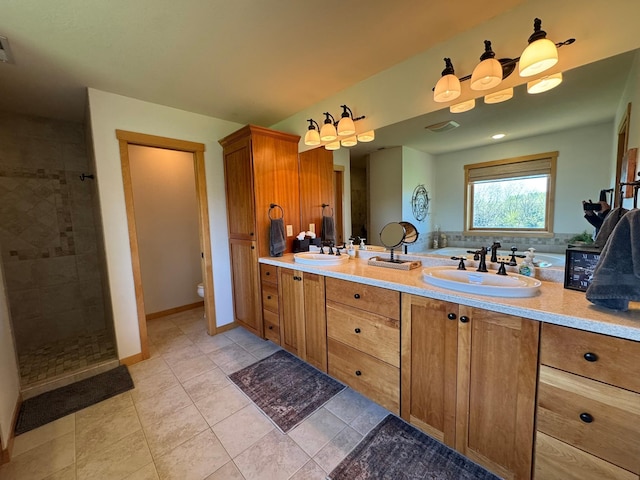 full bath with double vanity, tile patterned flooring, a tile shower, a sink, and toilet