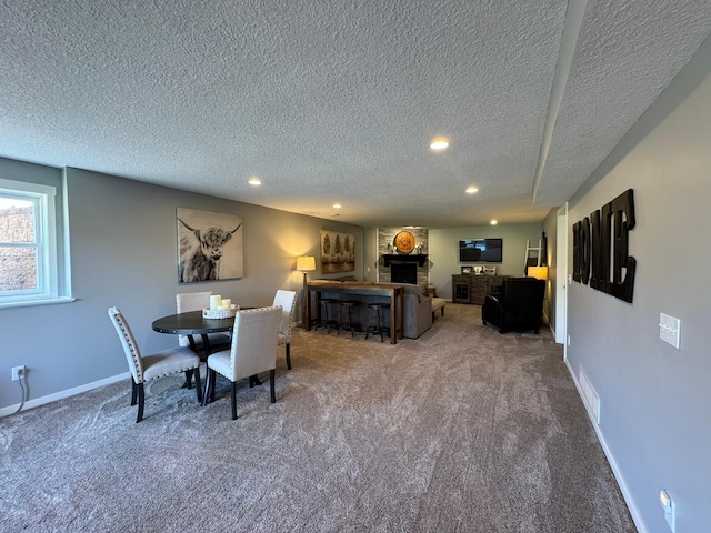 dining area with carpet floors, recessed lighting, a textured ceiling, and a large fireplace