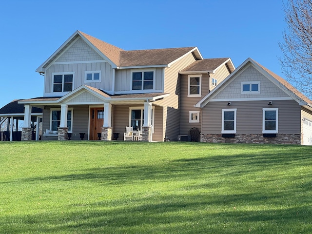 craftsman inspired home featuring board and batten siding, stone siding, a front yard, and a porch