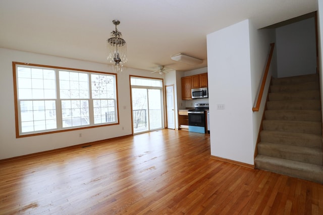 1728 Riverside Dr, Shakopee, MN 55379 - unfurnished living room with stairway, baseboards, a ceiling fan, and light wood-style floors