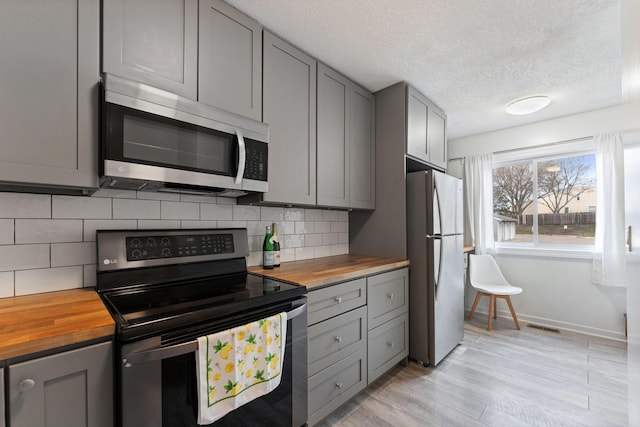 421 Robert St S, Saint Paul, MN 55107 - kitchen featuring tasteful backsplash, butcher block counters, appliances with stainless steel finishes, gray cabinetry, and visible vents