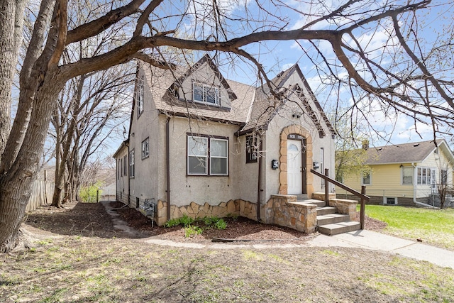 view of front of home featuring stucco siding, fence, and roof with shingles