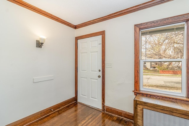 doorway featuring ornamental molding, dark wood finished floors, and baseboards