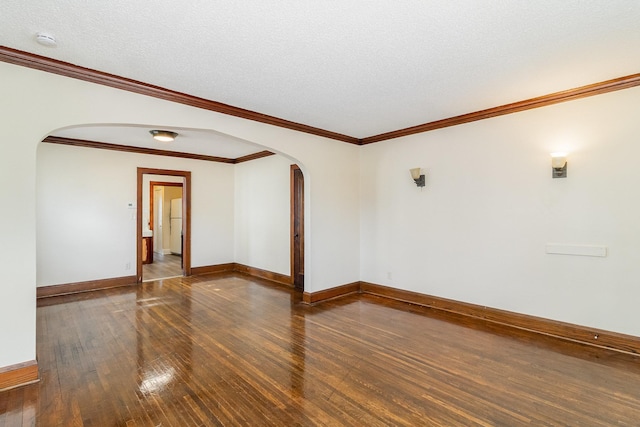 empty room with baseboards, arched walkways, hardwood / wood-style flooring, and crown molding