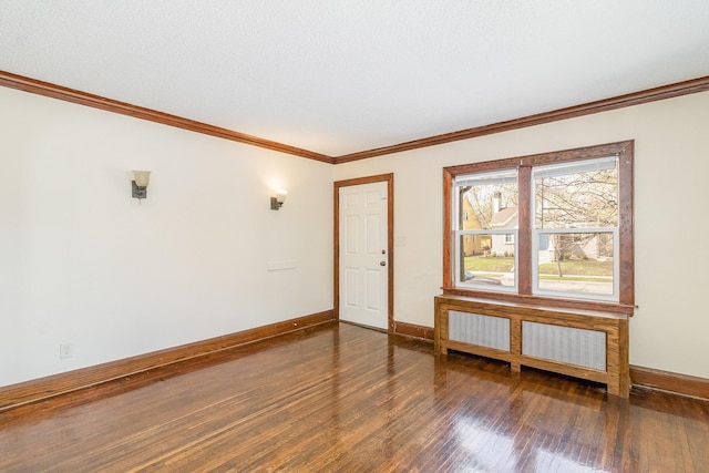 spare room with ornamental molding, wood finished floors, and baseboards