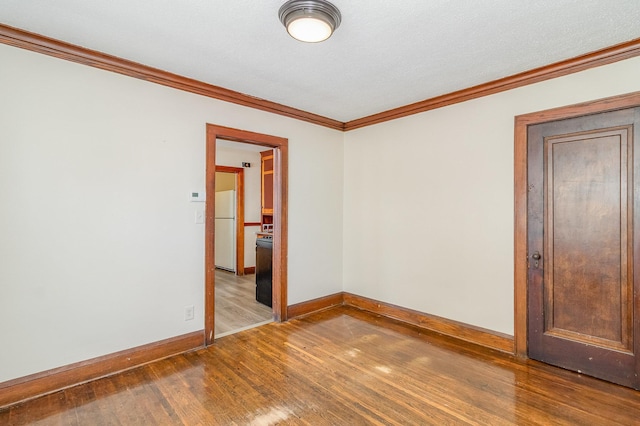 spare room featuring wood finished floors, ornamental molding, and baseboards