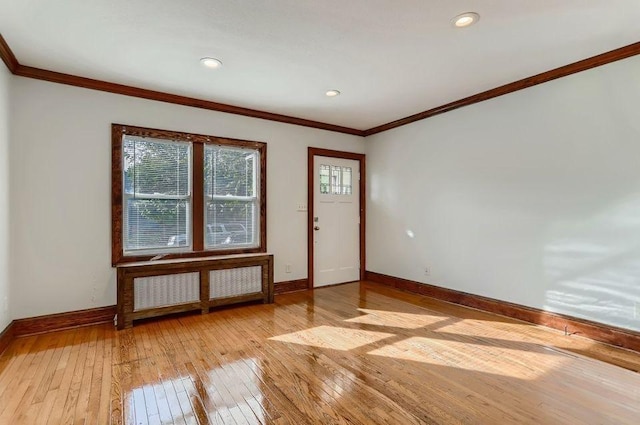 foyer entrance featuring radiator heating unit, ornamental molding, light wood finished floors, and baseboards