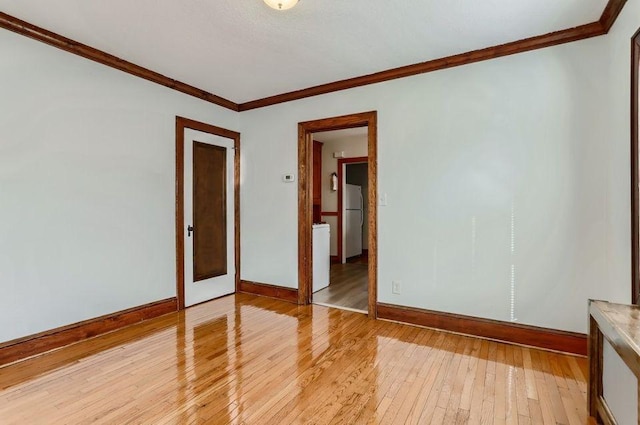 unfurnished room with crown molding, light wood-type flooring, and baseboards