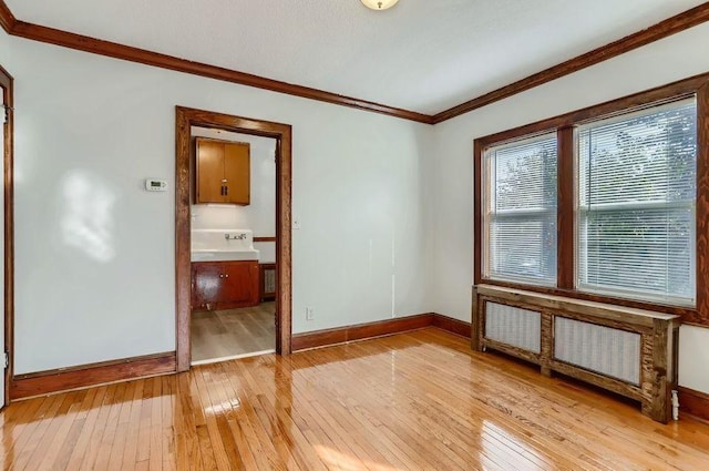 unfurnished room with ornamental molding, light wood finished floors, and baseboards