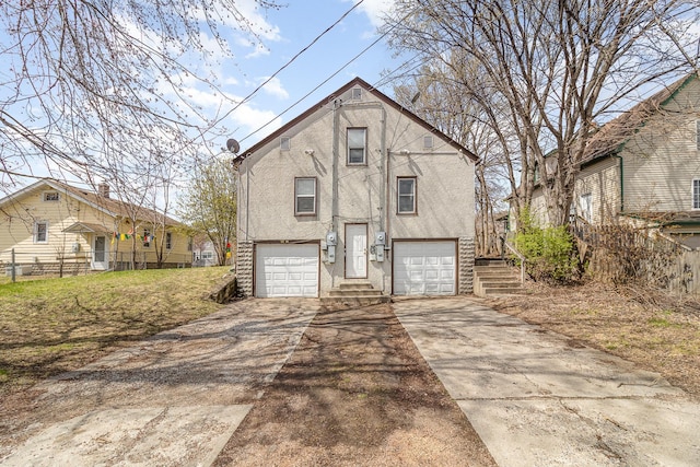bi-level home with fence, stucco siding, driveway, and an attached garage