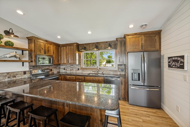11831 Gulden Ave NW, Maple Lake, MN 55358 - kitchen featuring stainless steel appliances, a peninsula, dark stone counters, tasteful backsplash, and a breakfast bar