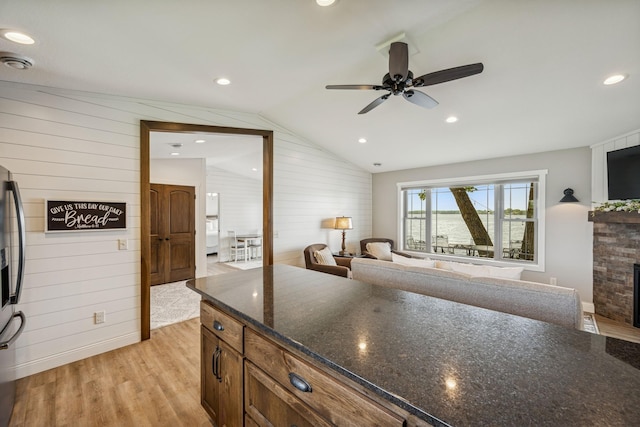 11831 Gulden Ave NW, Maple Lake, MN 55358 - kitchen featuring wood walls, light wood finished floors, a fireplace, vaulted ceiling, and a ceiling fan