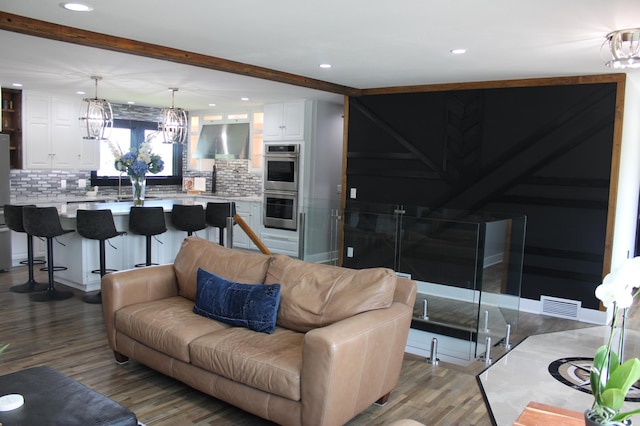 living room featuring recessed lighting, wood finished floors, beam ceiling, and a chandelier