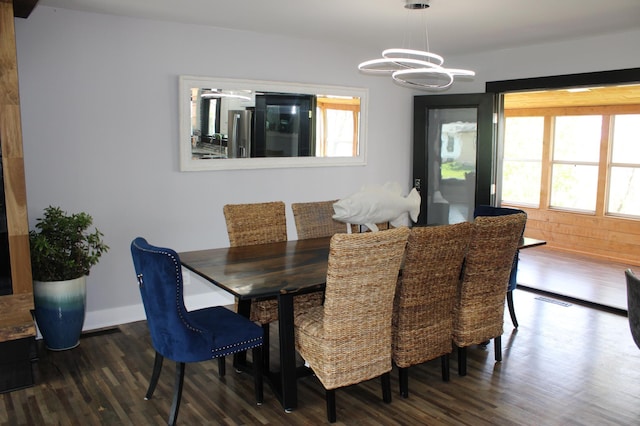dining area featuring dark wood-style floors, a chandelier, and baseboards