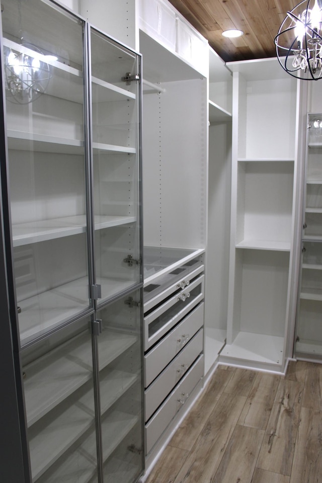 spacious closet featuring wood finished floors and a chandelier