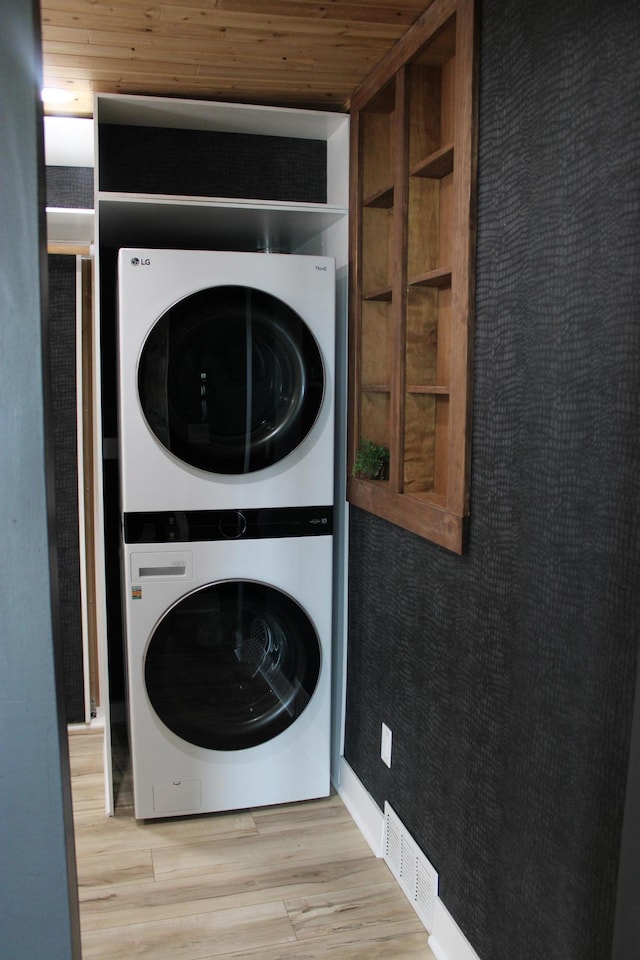 washroom with stacked washer / drying machine, wood finished floors, and wood ceiling