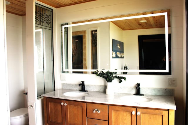 bathroom featuring wood ceiling, double vanity, and toilet