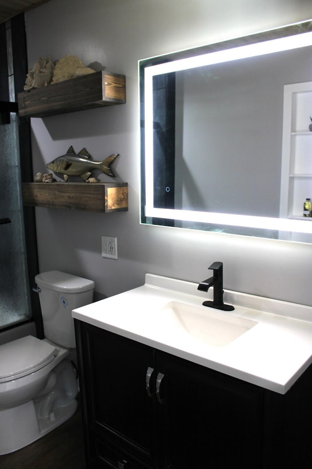 bathroom with vanity, toilet, and a shower