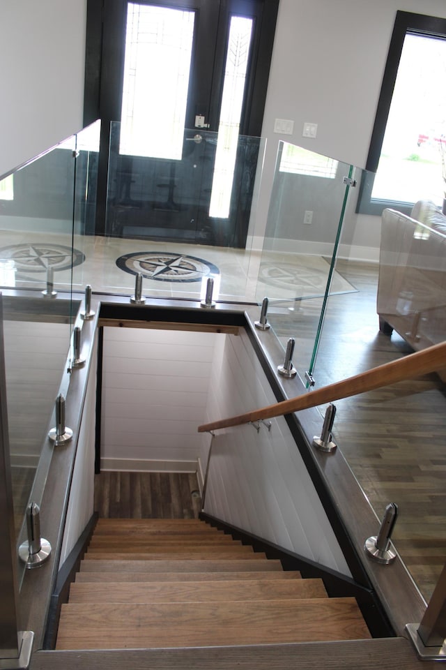 stairs with healthy amount of natural light, wood finished floors, and baseboards