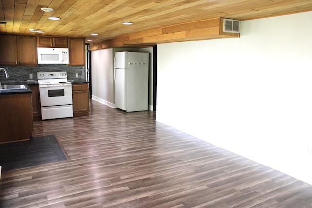 kitchen featuring white appliances, a sink, dark countertops, dark wood-style floors, and tasteful backsplash