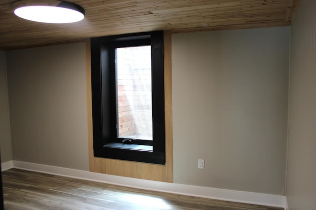 empty room featuring wood ceiling, baseboards, and wood finished floors