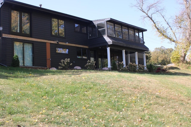 rear view of property with a lawn and a sunroom