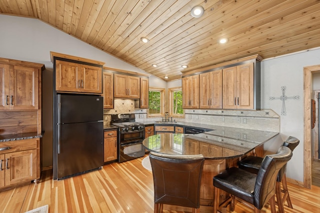 11847 Gulden Ave NW, Maple Lake, MN 55358 - kitchen featuring black appliances, vaulted ceiling, wooden ceiling, brown cabinetry, and a breakfast bar area