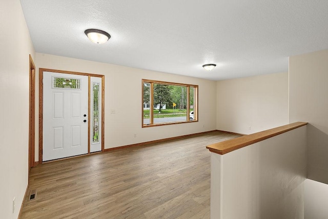 423 State St E, Grey Eagle, MN 56336 - entryway with baseboards, visible vents, a textured ceiling, and light wood finished floors
