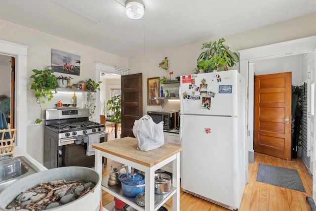650 Pierce St NE, Minneapolis, MN 55413 - kitchen with open shelves, black microwave, gas stove, light wood finished floors, and freestanding refrigerator