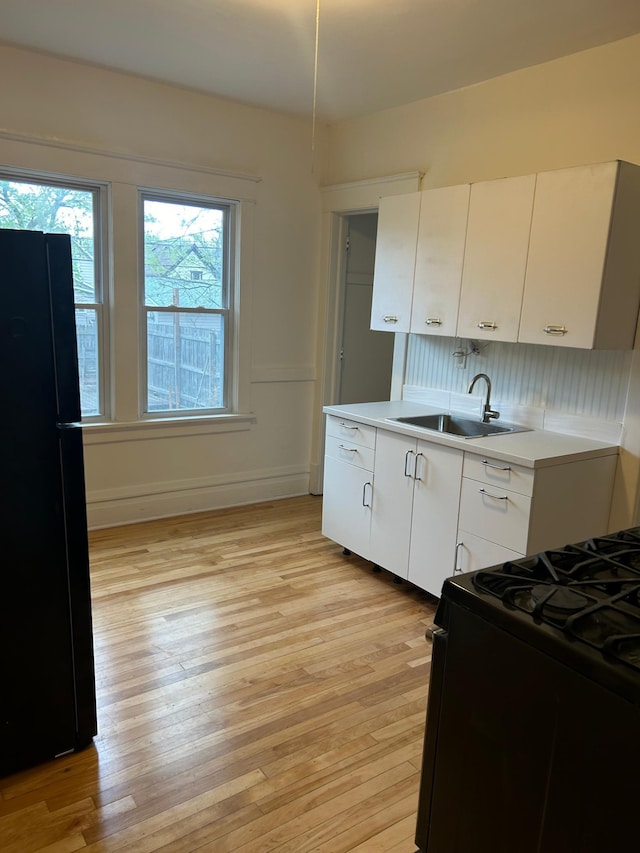 650 Pierce St NE, Minneapolis, MN 55413 - kitchen with a sink, light wood finished floors, black appliances, and white cabinets
