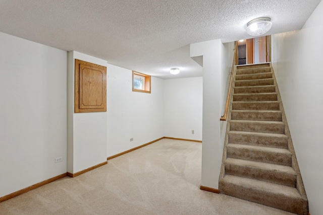 basement with stairs, a textured ceiling, baseboards, and light carpet
