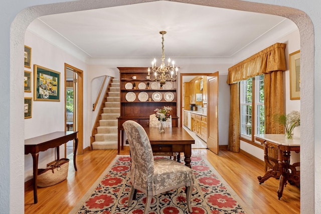 1804 Pinehurst Ave, Saint Paul, MN 55116 - dining space with light wood-style floors, a chandelier, arched walkways, stairway, and crown molding
