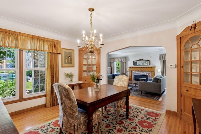 1804 Pinehurst Ave, Saint Paul, MN 55116 - dining space featuring arched walkways, light wood-type flooring, a premium fireplace, a chandelier, and ornamental molding