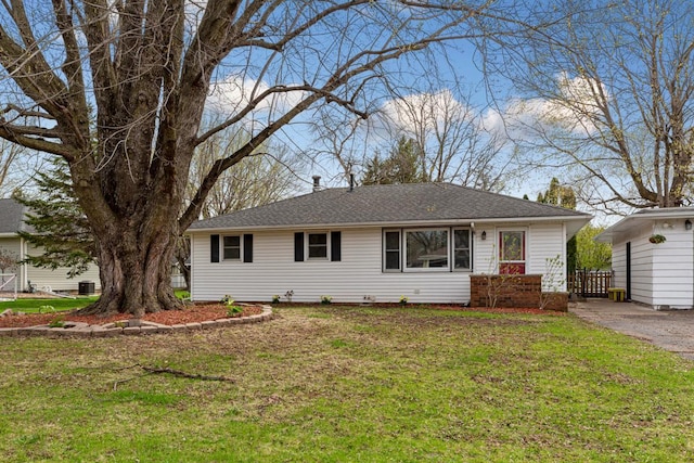 ranch-style home featuring a shingled roof and a front lawn