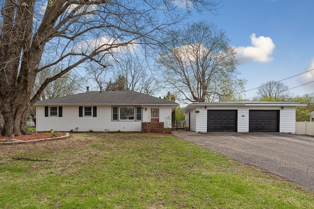 ranch-style home featuring a front yard, an outbuilding, fence, and a detached garage