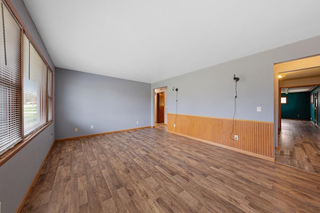 empty room with a wainscoted wall, wooden walls, and wood finished floors