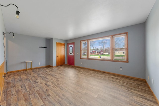 unfurnished living room with wood finished floors and baseboards